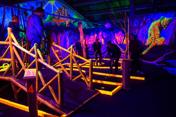Glow in the dark midgetgolfbaan bij Posta7 met houten bruggetje en lichtgevende jungle