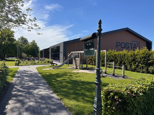 De entree van Posta7 met het pad door de tuin en het Posta7-logo op de hal
