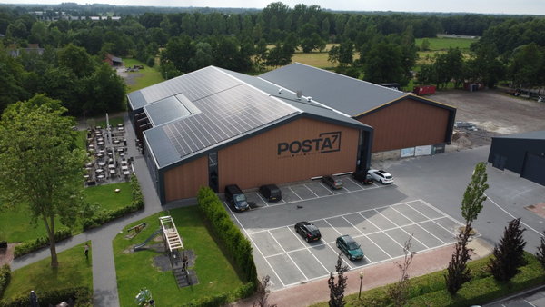 Luchtfoto van de activiteitenhal van Posta7 met zonnepanelen en parkeerterrein