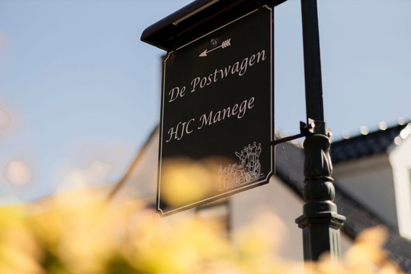 Uithangbord De Postwagen en HJC Manege aan de lantaarnpaal voor het pand