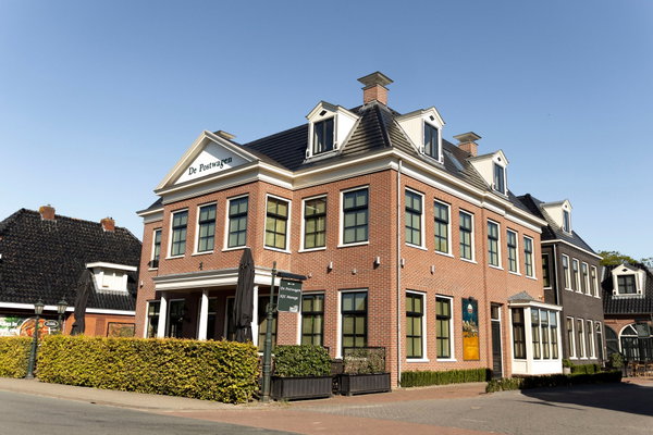 De voorgevel van De Postwagen aan de Hoofdstraat in Tolbert met het terras en de parasols