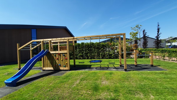 Houten klimtoestel met glijbaan op het grasveld van de speeltuin bij Posta7
