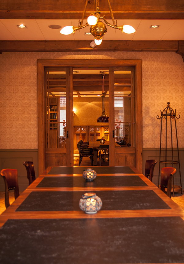 Doorkijk naar de eetzaal met houten tafels in restaurant De Postwagen