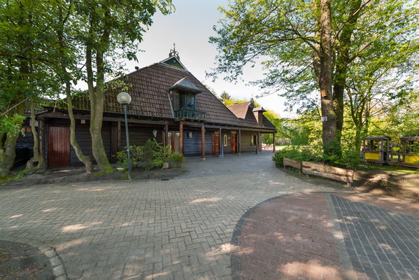 Overdekte doorrit en bijgebouw van De Postwagen onder de bomen