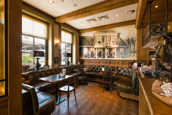Zitgedeelte met lederen banken en historische wandschildering in restaurant De Postwagen