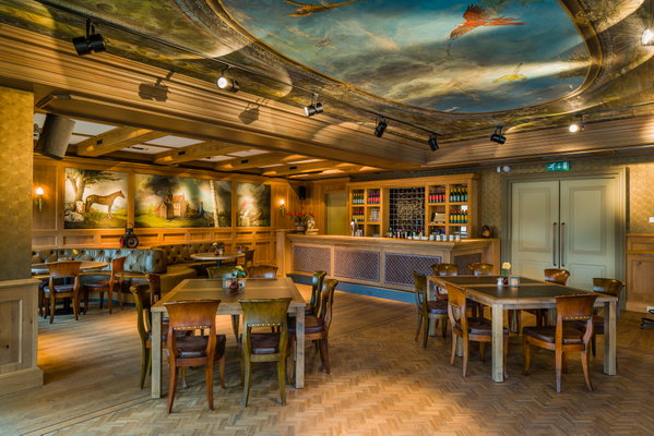 Zaal Dorpszicht met houten tafels, bar en wandschilderingen bij De Postwagen