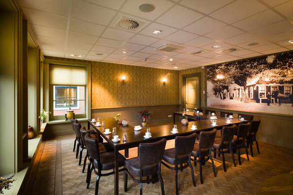 Vergaderzaal Tuigenkamer met gedekte vergadertafel en historische wandfoto