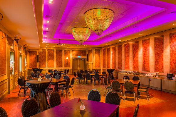 Feestzaal De Doorrit met paarse ledverlichting en gedekte tafels