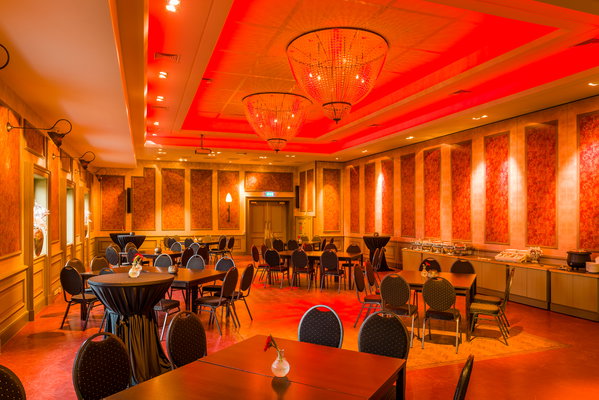 Feestzaal De Doorrit in rood licht met ronde tafels en statafels