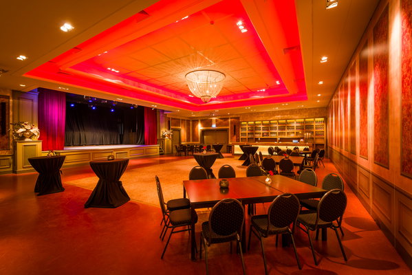 Zaal 't Koetshuis in rood en roze licht met kroonluchter