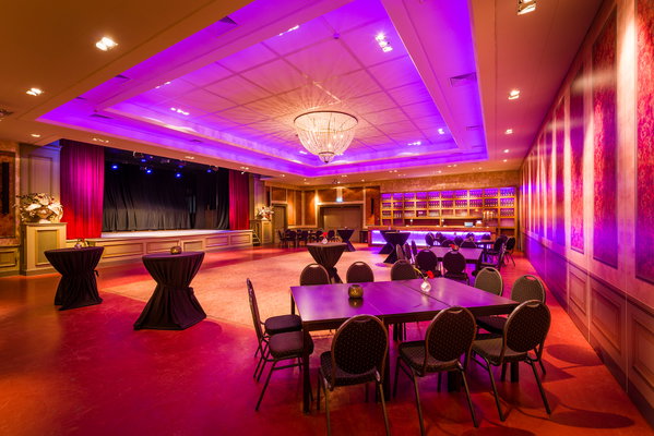 Zaal 't Koetshuis met paarse sfeerverlichting en podium