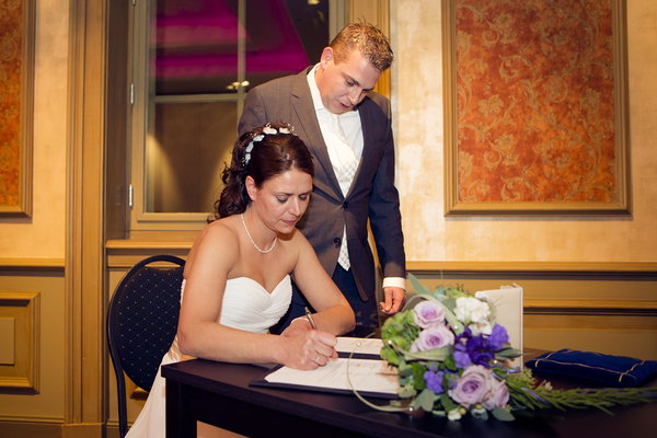 Bruid tekent de huwelijksakte aan tafel met bloemen bij De Postwagen