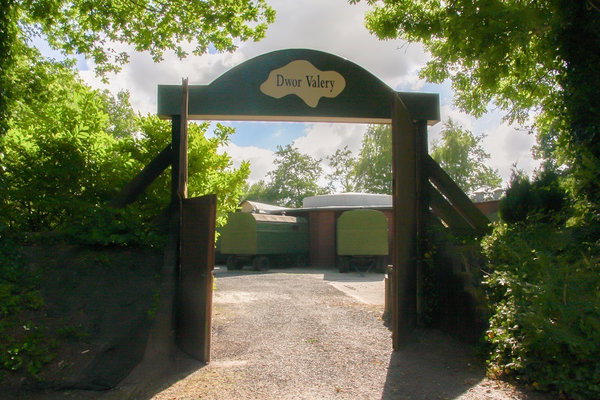 Houten toegangspoort van de groepsaccommodatie met zicht op de pipowagens