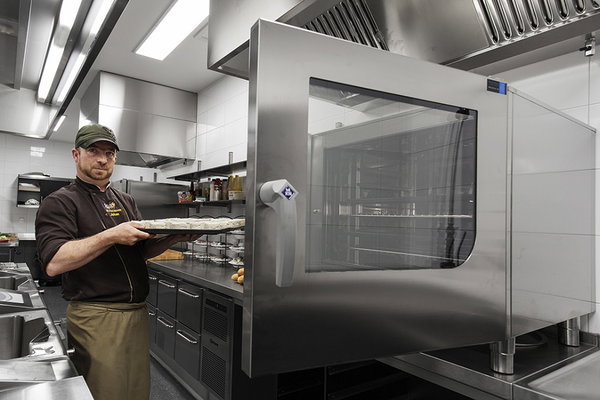 Kok haalt een plaat uit de combisteamer in de keuken van De Postwagen