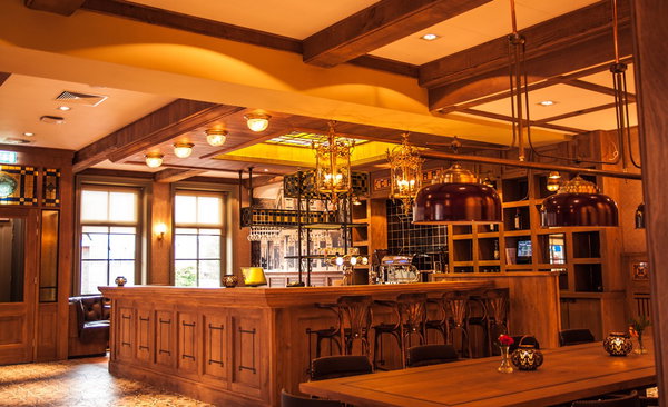 De houten bar van restaurant De Postwagen met koperen biertanks