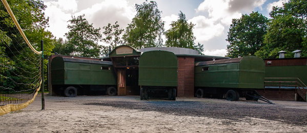 Groene pipowagens rondom het centrale plein van de groepsaccommodatie De Mobiel Loges