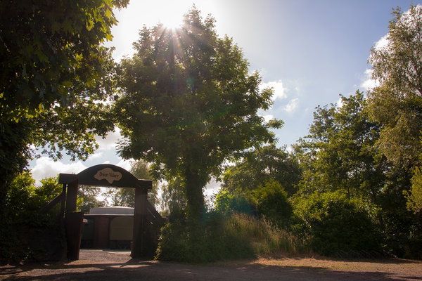Poort van de groepsaccommodatie tussen de bomen met tegenlicht