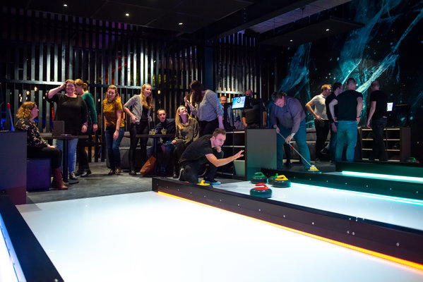 Groep speelt Fun Curling op de verlichte baan bij Posta7