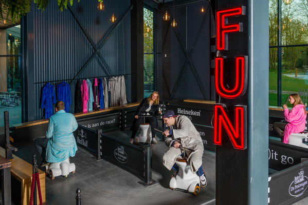 De WC-pot-Race-baan van Posta7 met badjassen aan de wand en het rode FUN-neon