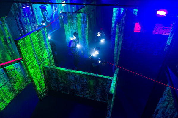 De lasergame-arena van Posta7 in blacklight met rook en laserstralen