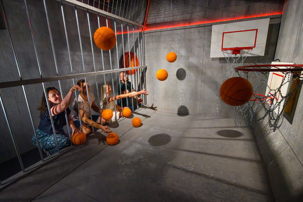 Deelnemers gooien basketballen door de tralies van een cel tijdens de Jail Challenge bij Posta7