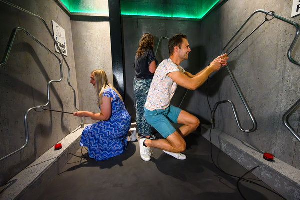 Twee deelnemers bedienen samen een buizenpuzzel in een cel van de Jail Challenge