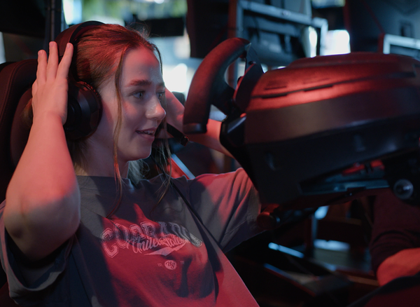 Deelneemster met headset in de racesimulator van de Posta Race Experience