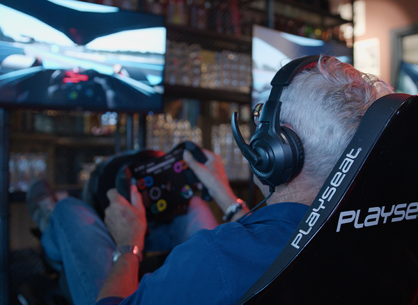 Coureur met stuur en headset in de racesimulator bij Posta7